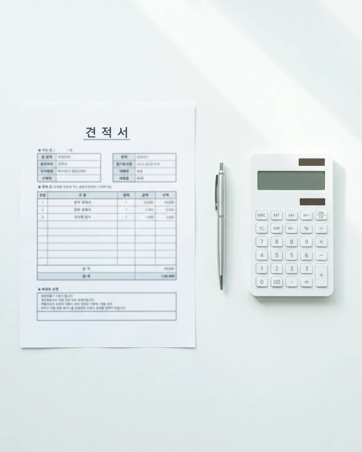 흰 책상 위에 놓인 견적서와 펜, 계산기